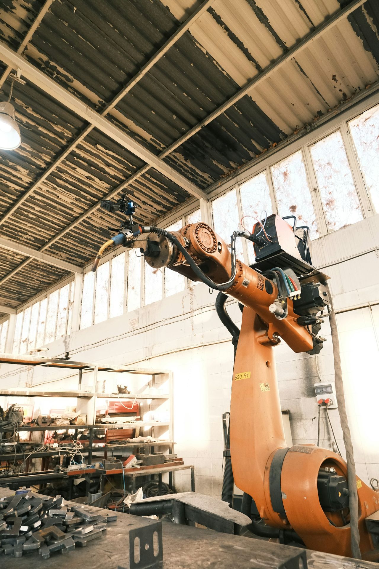 A large orange robot in a building with lots of tools